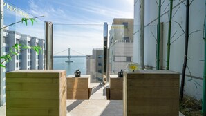 A modern building with a glass facade, wooden benches, and a view of a bridge in the background. - Gwanganri The Club hotel (Busan)