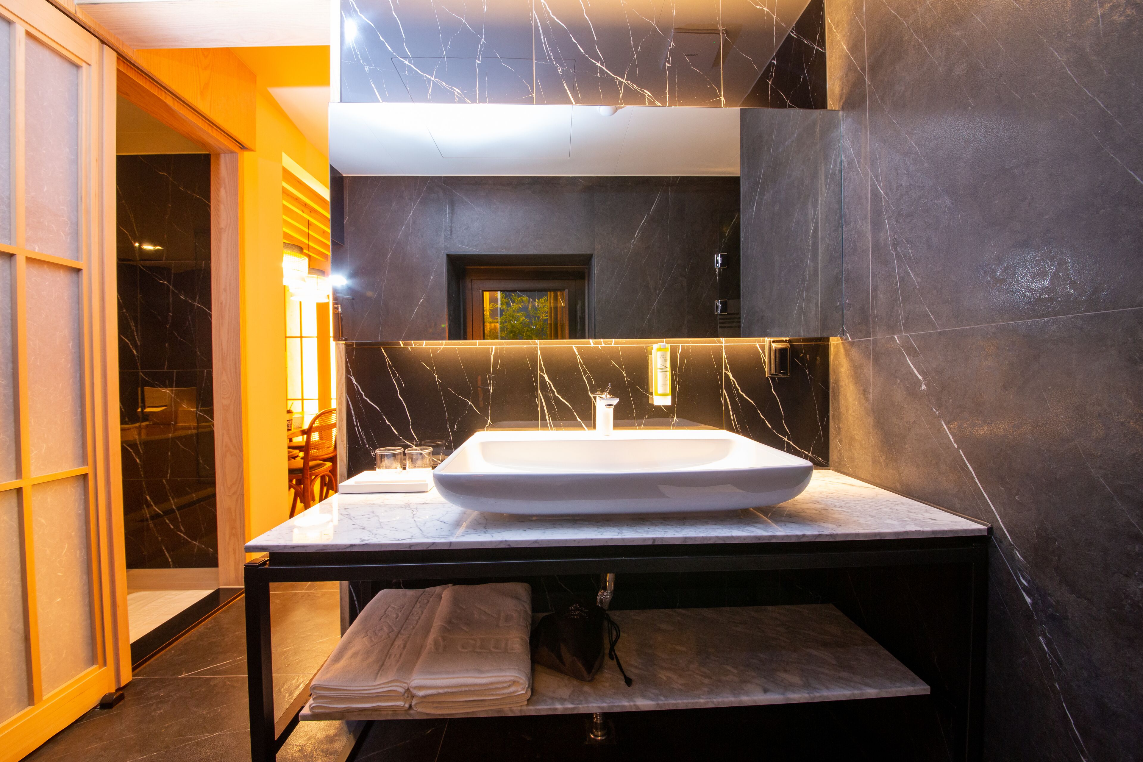 A modern bathroom with a large marble sink, a towel rack, and a mirror above the sink.