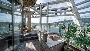 A modern balcony with glass walls, wooden flooring, and seating. - Gwanganri The Club hotel (Busan)