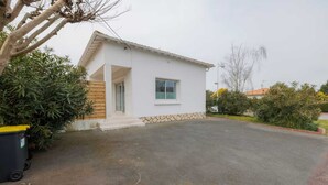 A single-story building with a white exterior, a small window, and a paved driveway. - Villa Luxe Plages et Commerces à Pieds (carnac)