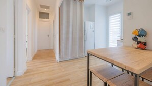 A hallway with a wooden floor, a white door, a patterned curtain, and a table with benches. - Villa Luxe Plages et Commerces à Pieds (carnac)