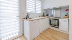 A modern kitchen with white cabinetry, a dishwasher, a microwave, and an oven. - Villa Luxe Plages et Commerces à Pieds (carnac)
