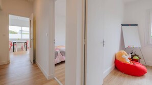 A room with a bed, a red bean bag, a whiteboard, and a view of a balcony with outdoor furniture. - Villa Luxe Plages et Commerces à Pieds (carnac)