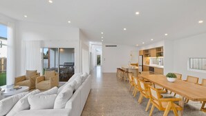 A modern living room with a sofa, a dining table with chairs, and a kitchen area with a refrigerator and cabinets. - Casa Bella on Beach in Cowes (Cowes)
