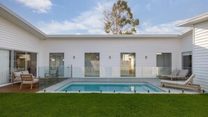 A modern house with a swimming pool, glass doors, and outdoor seating. - Casa Bella on Beach in Cowes (Cowes)