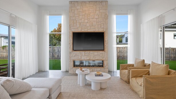 A modern living room with a stone fireplace, a flat-screen TV, and a comfortable seating area. - Casa Bella on Beach in Cowes (Cowes)