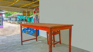 Una mesa de madera en un espacio exterior cubierto con techo de lámina corrugada.