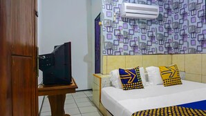 Una habitación de hotel con una cama, un televisor sobre un mueble y una pared con diseño.