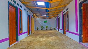 Un pasillo con puertas de madera, suelo de baldosas y techo con vigas de madera.