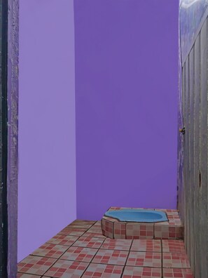 A small bathroom with purple walls, a tiled floor, and a blue bathtub. - Hotel O Nusasari Guest House (Sukabumi)