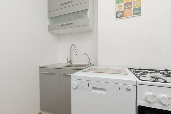 Une cuisine de taille réduite équipée d’un lave-vaisselle, d ’un évier et d’une cuisinière à gaz.