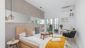 Une chambre moderne comprenant un lit, une table de chevet, une chaise, un bureau et une grande fenêtre.