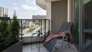 Un balcon avec une chaise, une petite table et un pot de fleurs.