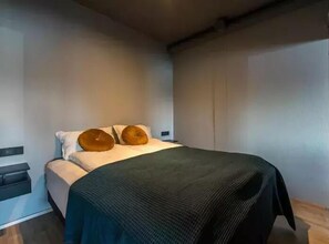 Une chambre à coucher moderne avec un lit, deux oreillers, une table de chevet et un plancher en bois.