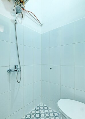 A bathroom with white tiles, a shower with a handheld showerhead, and a toilet. - OYO 91596 Hotel Rajadani (Yogyakarta)