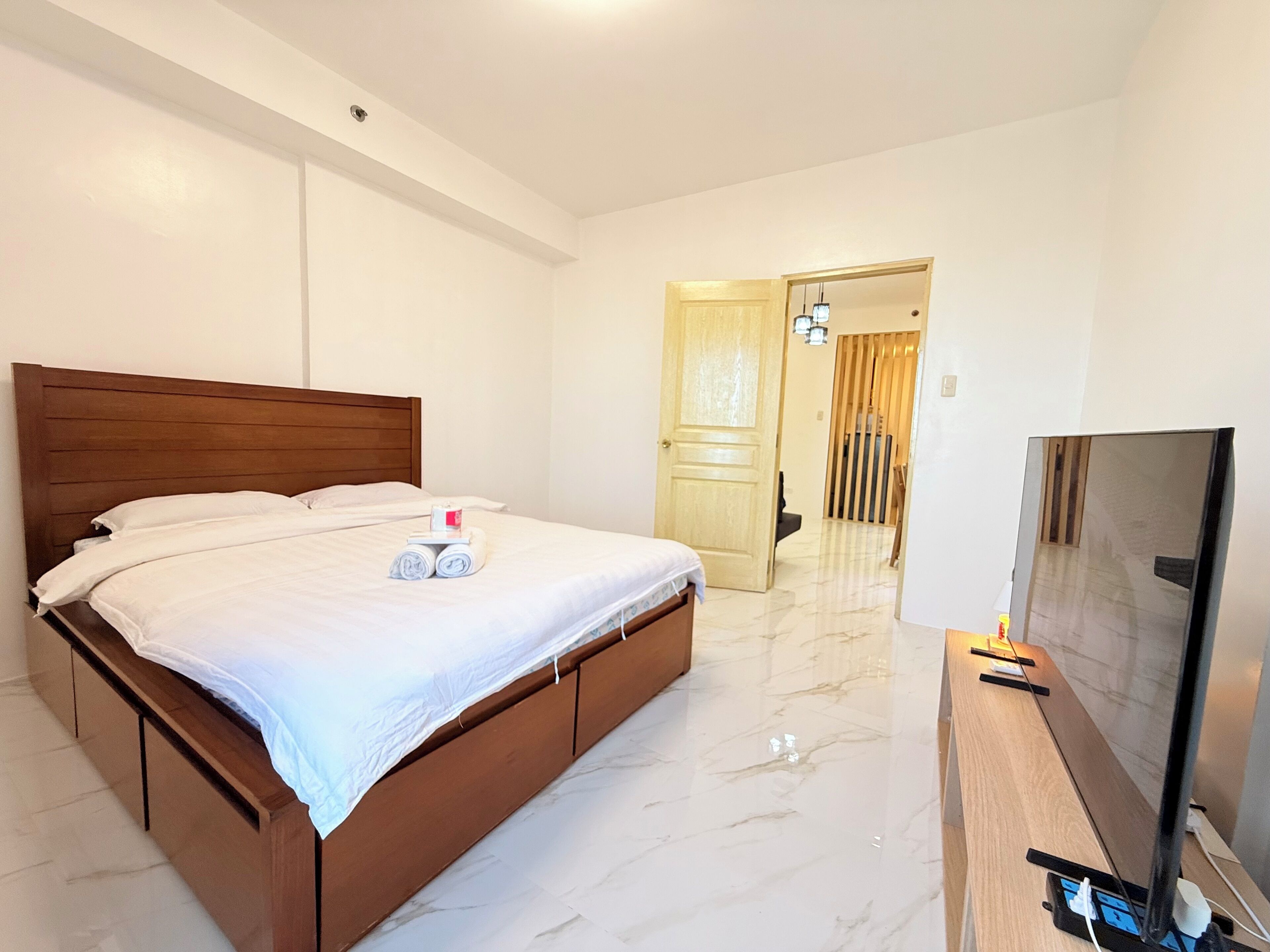 A hotel room with a large bed, a TV, and a wooden door.
