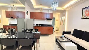 A modern living room with a sofa, coffee table, and dining area with chairs and a table. - Malate Bayview Mansion (Manila)