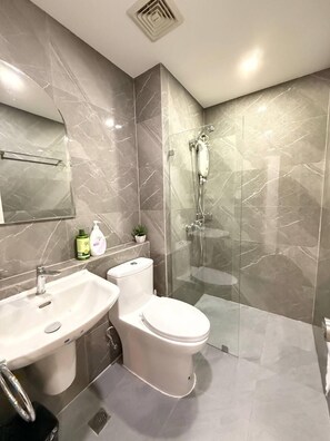 A modern bathroom with a glass-enclosed shower, two sinks, and a toilet. - Malate Bayview Mansion (Manila)