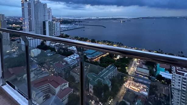 A high-rise building with a view of a body of water and surrounding cityscape. - Malate Bayview Mansion (Manila)