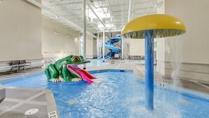 An indoor water park with a large frog sculpture, a water slide, and a pool area. - Rocky Mountain Haven - Mountain Views | Pool & Waterslide! (Canmore)