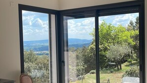 Un dormitorio con cama, una silla, ventilador de techo y vistas a un jardín a través de puertas de vidrio grandes.