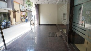 A clean, modern lobby with a tiled floor and glass doors leading to a room. - Hotel Royal Rosette (New Delhi)