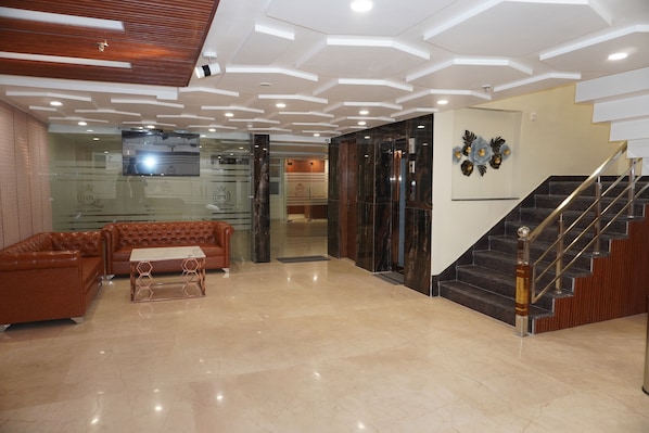 A lobby with a modern design, featuring a wooden ceiling, a staircase, and a seating area with a sofa and coffee table.