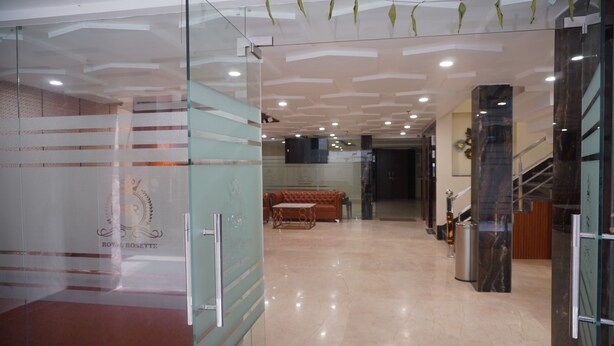 A modern lobby with a glass partition, a marble floor, a staircase, and a sofa. - Hotel Royal Rosette (New Delhi)