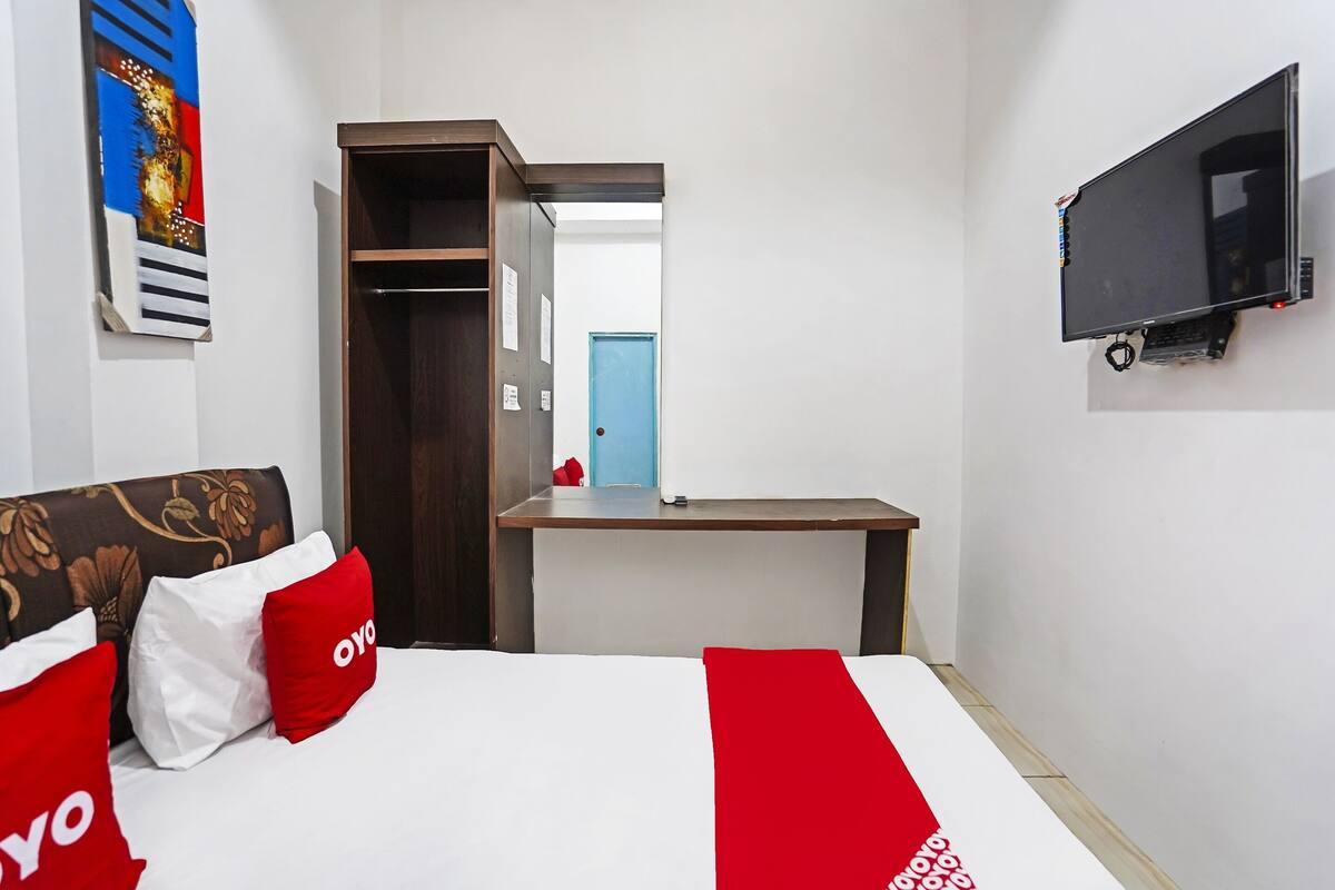 Una habitación de hotel con cama, escritorio, televisor y puerta que da a otra habitación.