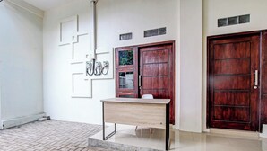 Una habitación con un escritorio, dos puertas de madera y una pared blanca con patrones geométricos.