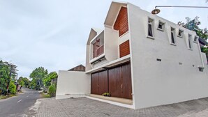 Un edificio moderno con un amplio portón de garaje, un techo inclinado y un pequeño balcón.