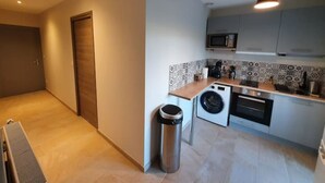 A compact kitchen with a washing machine, microwave, and a trash bin. - Chez Arnaud (Saint-Jean-Saint-Maurice-sur-Loire)