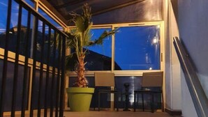 A staircase leading to a covered outdoor area with a potted plant and seating. - Chez Arnaud (Saint-Jean-Saint-Maurice-sur-Loire)