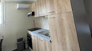 A compact kitchen with wooden cabinets, a stainless steel refrigerator, and a built-in oven. - Studio 30 m2 Dans Petit Port de Pêche (Centuri)