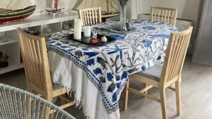 A dining area with a table set for four, a painting of a sailboat on the wall, and a decorative vase. - Appartement rez de Chaussée (Mandelieu-la-Napoule)