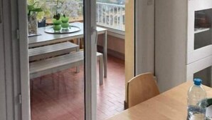 A balcony with a table and chairs, a water bottle on the table, and a view of the cityscape. - Appartement rez de Chaussée (Mandelieu-la-Napoule)