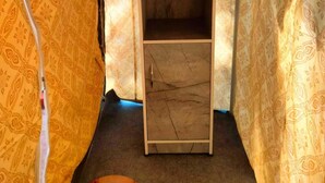 Une pièce étroite aux murs recouverts d’un papier peint à motifs, avec une armoire en bois et un meuble dont le motif imite le marbre.