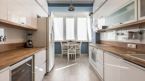 Moderni keittiö, jossa on valkoiset kaapit, puinen työtaso sekä ruokailutila, jossa on pöytä ja tuolit.