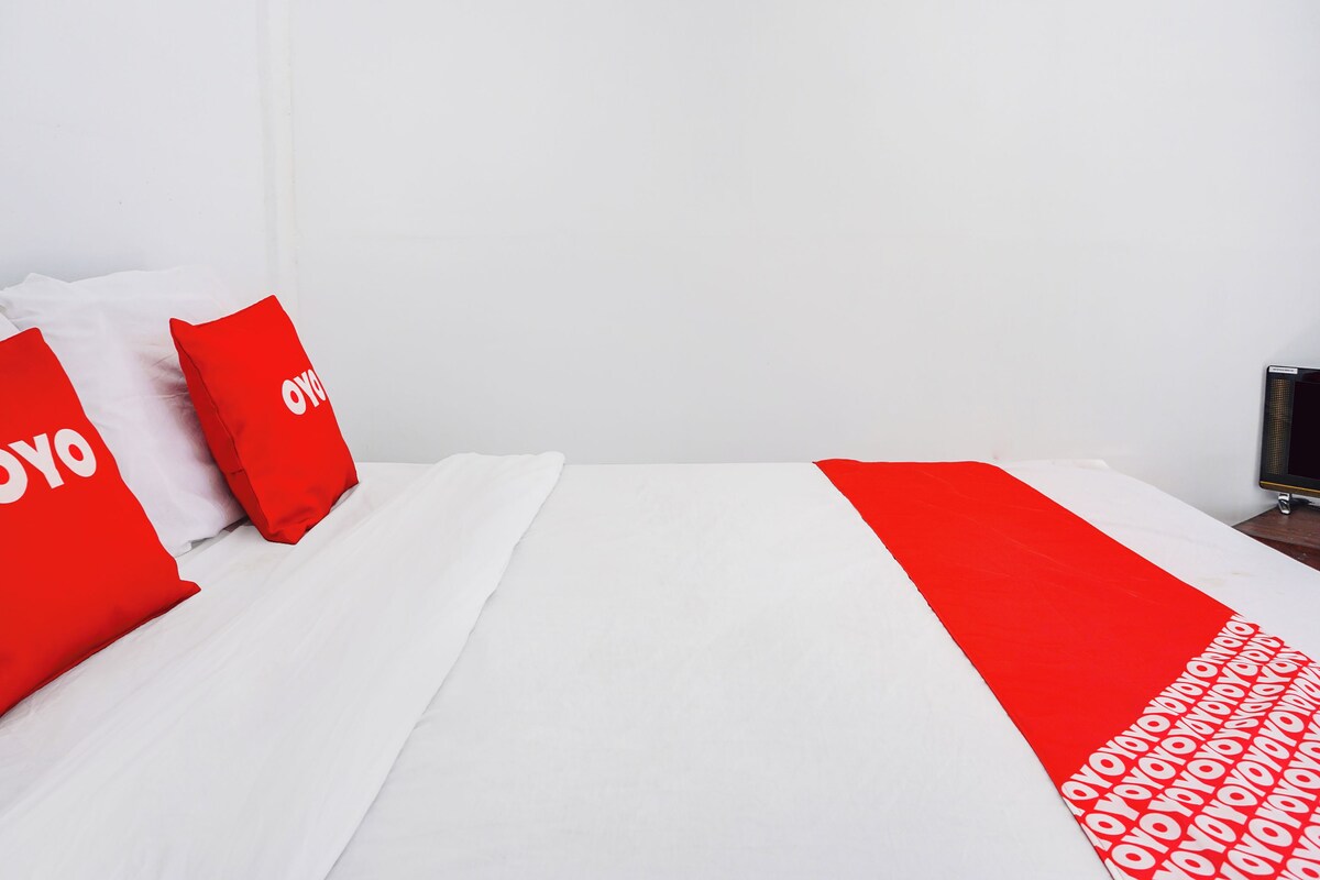 Ein Hotelzimmer mit einem Bett, weißer Bettwäsche und roten Kissen mit dem Schriftzug "YOYO".