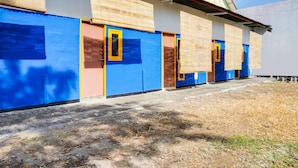 Une rangée de bâtiments aux murs bleus et beiges, avec quelques portes et un toit recouvert de tuiles.