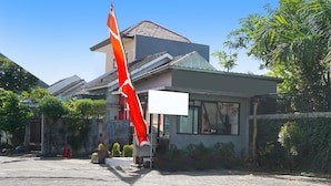 Un bâtiment moderne, orné d’un grand drapeau rouge bien visible, doté d’une grande fenêtre et d’un espace d’entrée pavé.