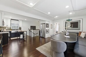 Uma cozinha moderna com uma ilha central, uma sala de jantar com mesa redonda e uma sala de estar com sofá.