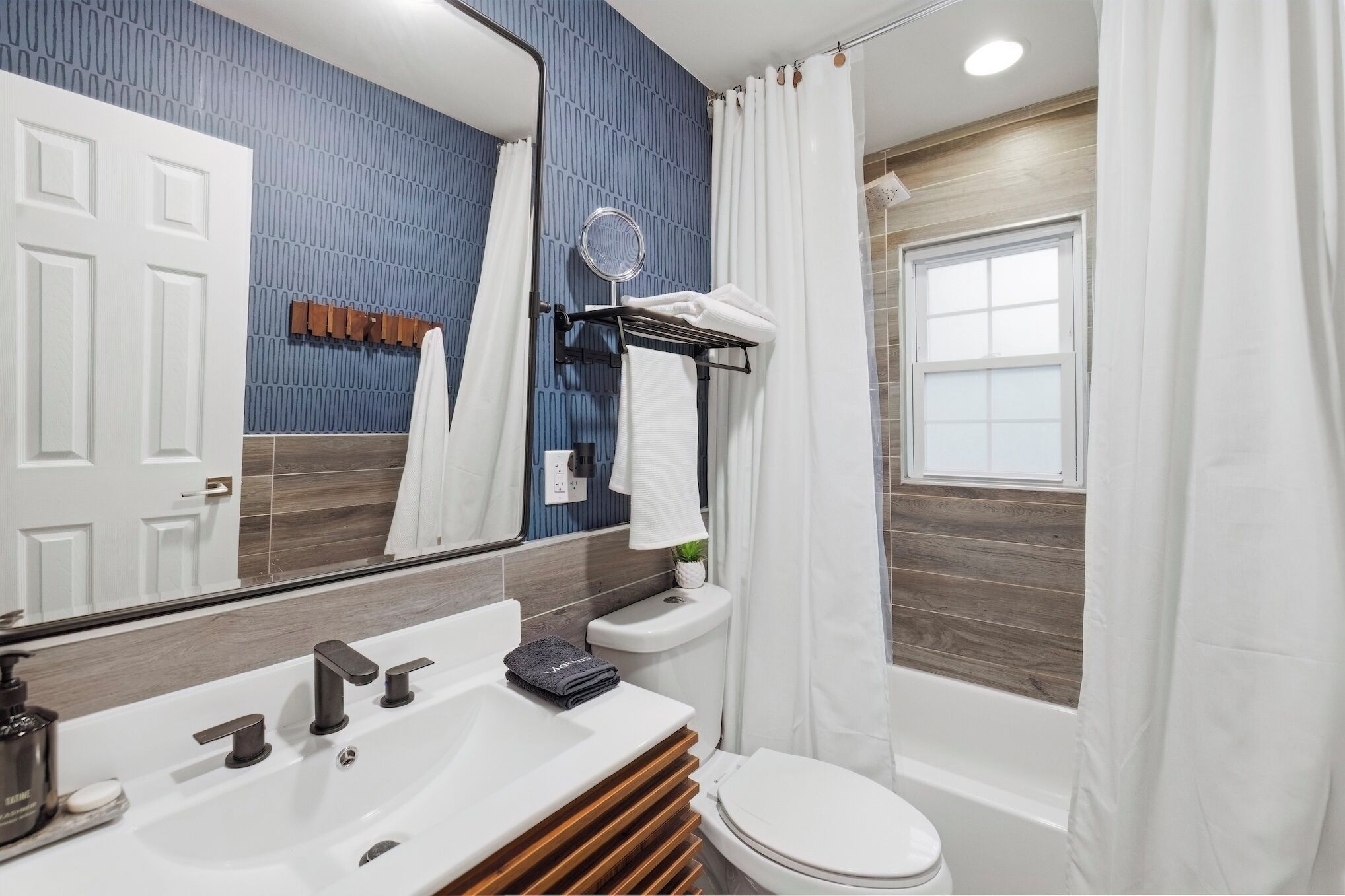 A modern bathroom with a white sink, black faucet, and a wooden vanity.