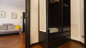 A modern room with a grey sofa, a black wardrobe, and wooden flooring.