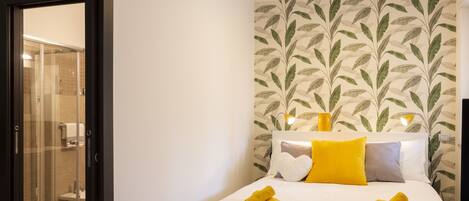A hotel room with a bed, a shower area, and a wall with a leaf pattern.