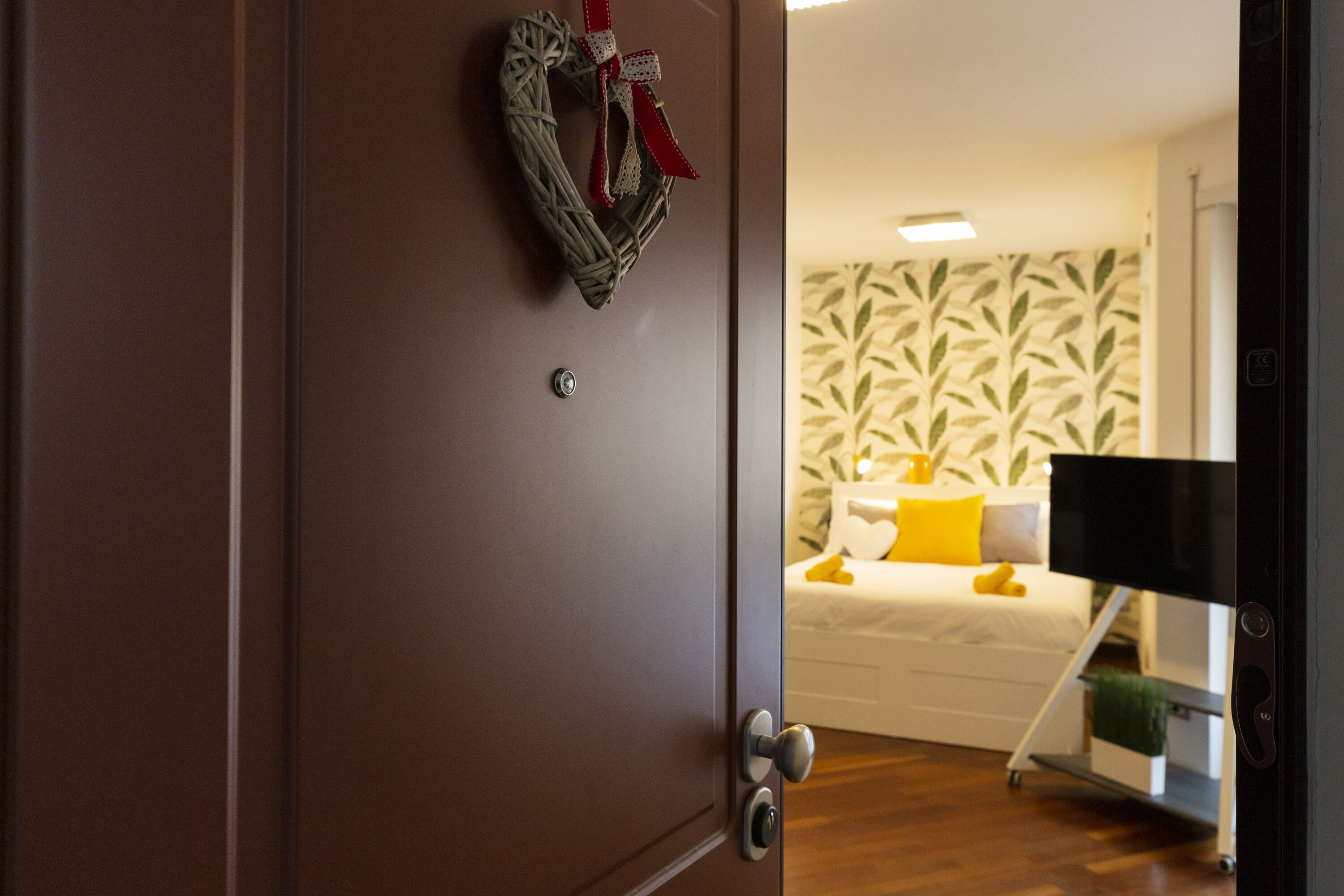 Une chambre avec un lit, un mur orné d’un motif de feuilles et une porte décorée d’une guirlande.