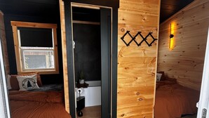 Acogedora habitación tipo cabaña con dos camas, un muro de madera, una ventana y un candelabro.