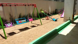 A playground with swings, a seesaw, and a slide. - RoyalGardens Kilimani View Palace Apart  (Nairobi)