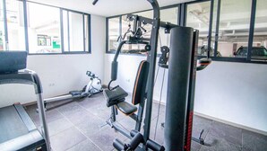 A gym with exercise equipment, a treadmill, and large windows. - RoyalGardens Kilimani View Palace Apart  (Nairobi)