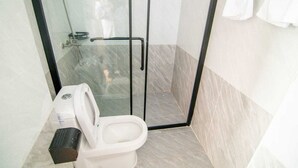 A modern bathroom with a glass-enclosed shower, a toilet, and a bench. - RoyalGardens Kilimani View Palace Apart  (Nairobi)